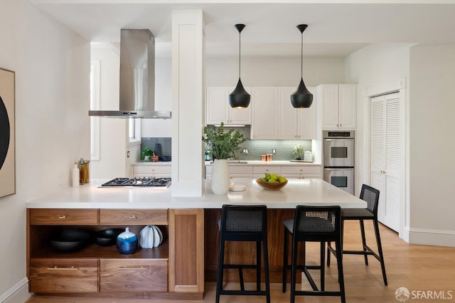 2864 Sacramento St, San Francisco, CA 94115 - kitchen featuring wall chimney exhaust hood, stainless steel appliances, decorative backsplash, baseboards, and white cabinetry
