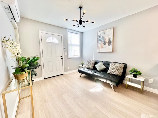 foyer entrance with light hardwood / wood-style floors, a notable chandelier, and a wall unit AC