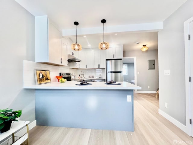 kitchen featuring kitchen peninsula, white cabinets, pendant lighting, appliances with stainless steel finishes, and tasteful backsplash