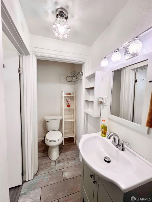 bathroom with vanity, toilet, and wood-type flooring