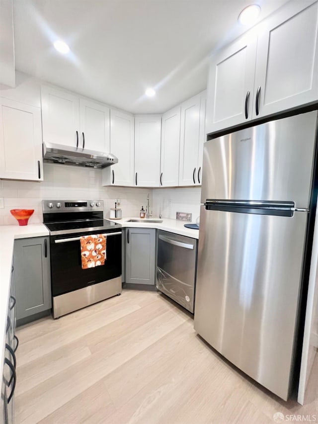 kitchen featuring white cabinets, sink, gray cabinetry, light hardwood / wood-style floors, and stainless steel appliances