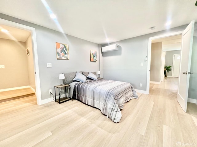 bedroom featuring light hardwood / wood-style floors and a wall mounted AC