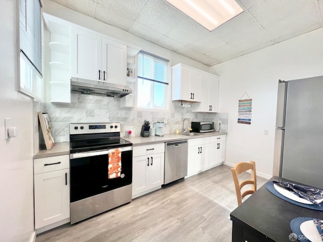 kitchen featuring white cabinetry, stainless steel appliances, light hardwood / wood-style floors, and tasteful backsplash