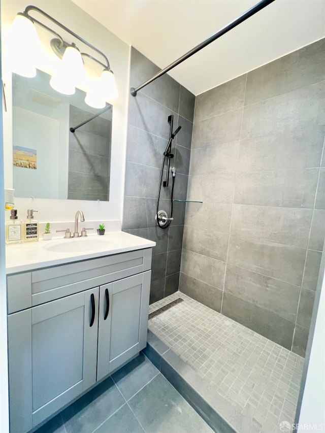 bathroom featuring vanity, tile patterned flooring, and tiled shower