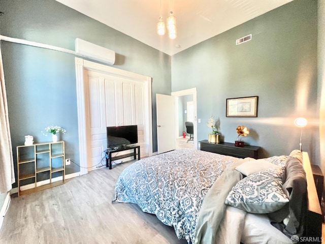 bedroom featuring a wall unit AC and light wood-type flooring