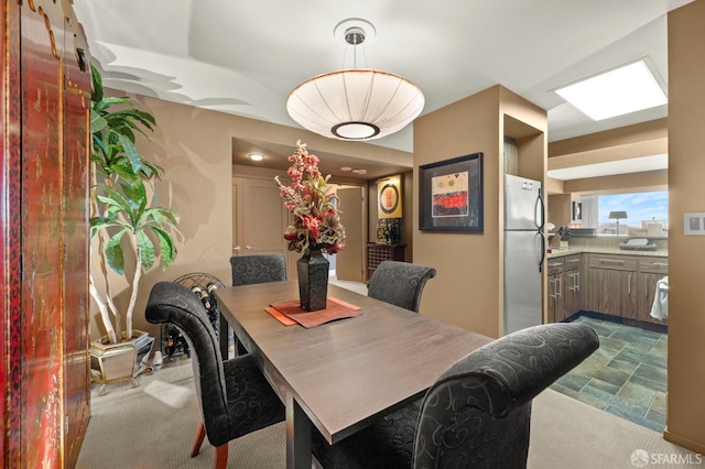 carpeted dining room featuring stone finish floor