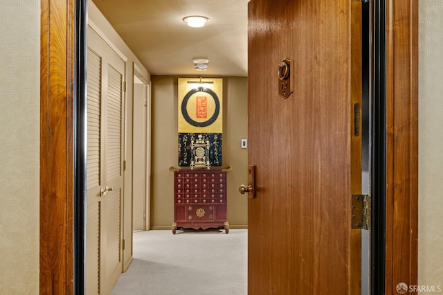 corridor featuring baseboards and carpet