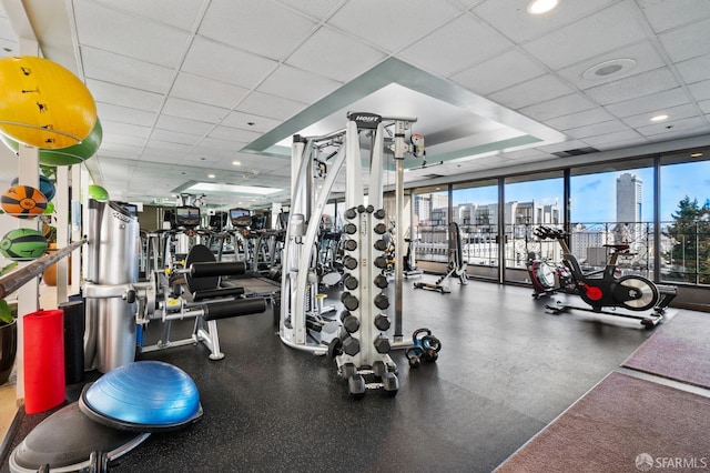 workout area with floor to ceiling windows and a drop ceiling