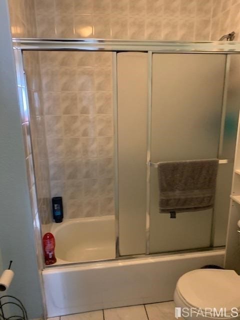 bathroom with bath / shower combo with glass door, toilet, and tile patterned flooring