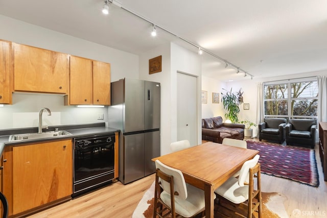 kitchen with stainless steel refrigerator, sink, light wood-type flooring, and black dishwasher