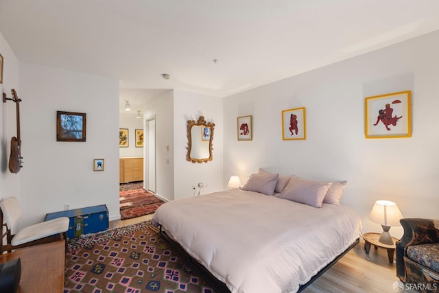 bedroom with wood-type flooring and ensuite bath