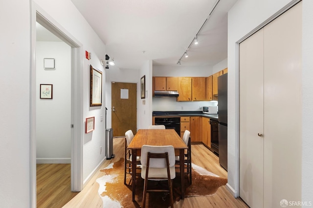 dining space featuring rail lighting and light hardwood / wood-style flooring