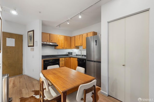 kitchen featuring sink, rail lighting, light hardwood / wood-style flooring, and black appliances