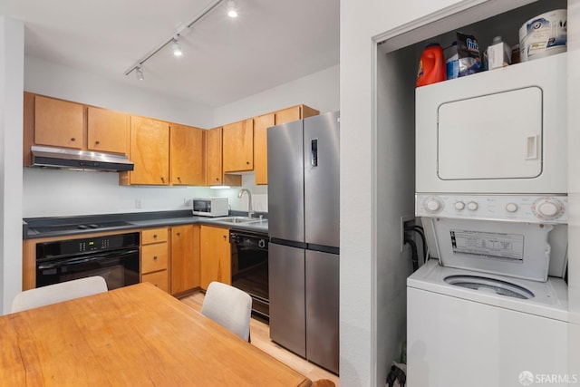 kitchen featuring black appliances, sink, stacked washer and dryer, and rail lighting