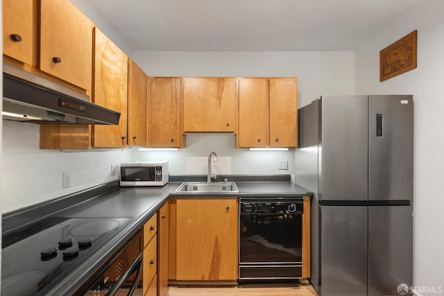 kitchen with dark countertops, black appliances, under cabinet range hood, and a sink