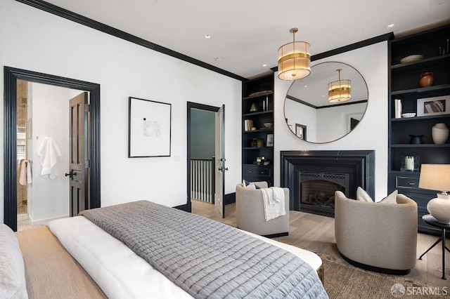 bedroom with baseboards, wood finished floors, ornamental molding, and a fireplace