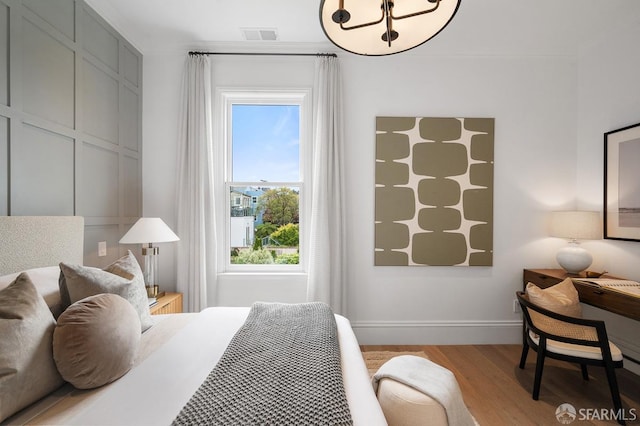 bedroom with visible vents, baseboards, and wood finished floors