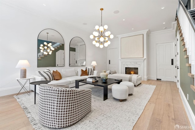 living area with a notable chandelier, light wood-type flooring, crown molding, and baseboards