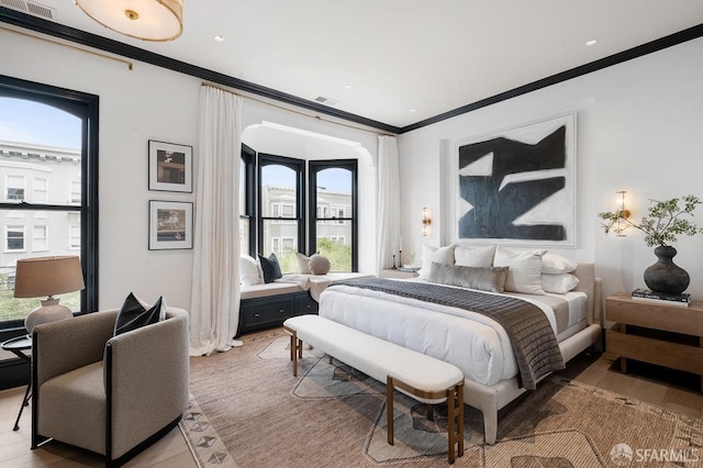 bedroom with light wood-style flooring, visible vents, and ornamental molding