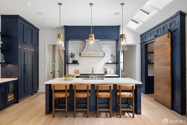 kitchen with decorative backsplash, a kitchen bar, light wood-style floors, and custom range hood