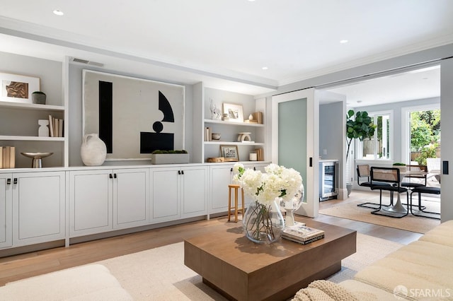 living area featuring visible vents, built in shelves, wine cooler, light wood-type flooring, and recessed lighting