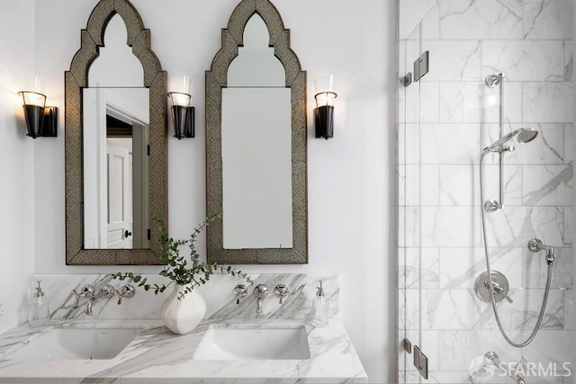 bathroom featuring a shower stall, double vanity, and a sink