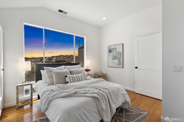 bedroom with wood finished floors, visible vents, baseboards, lofted ceiling, and recessed lighting