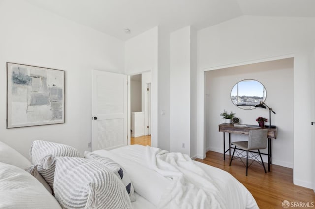 bedroom with baseboards, wood finished floors, and vaulted ceiling