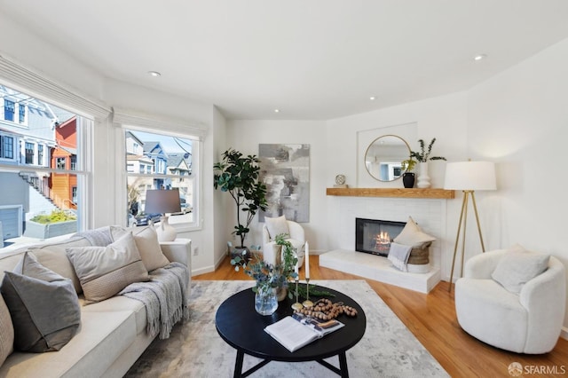 living room featuring a glass covered fireplace, recessed lighting, and wood finished floors