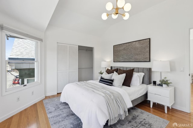 bedroom with a closet, lofted ceiling, an inviting chandelier, and wood finished floors