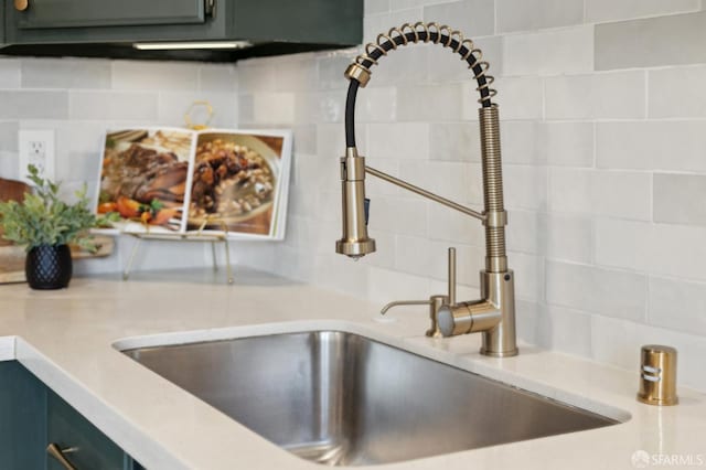 interior details with backsplash, light countertops, and a sink