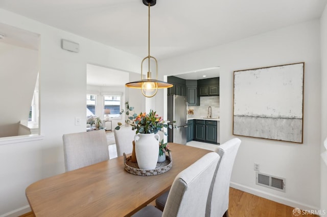 dining space with visible vents, baseboards, and light wood-style flooring