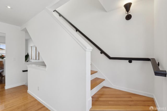 stairs with wood finished floors and baseboards