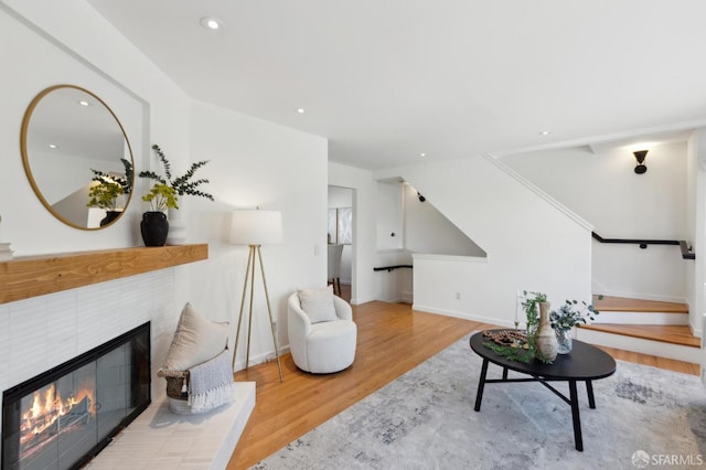 living area featuring wood finished floors, recessed lighting, baseboards, stairs, and a tile fireplace