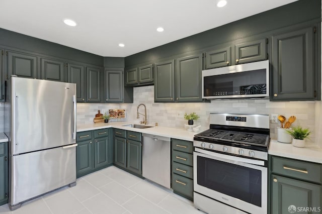 kitchen featuring a sink, backsplash, appliances with stainless steel finishes, and light countertops