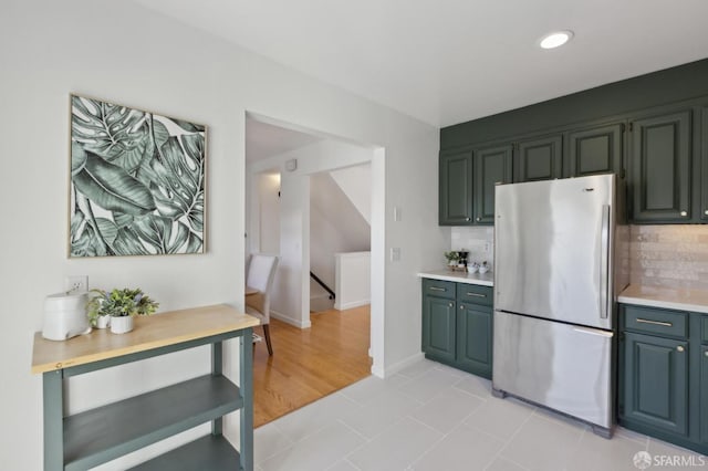 kitchen featuring tasteful backsplash, baseboards, light countertops, light tile patterned floors, and freestanding refrigerator