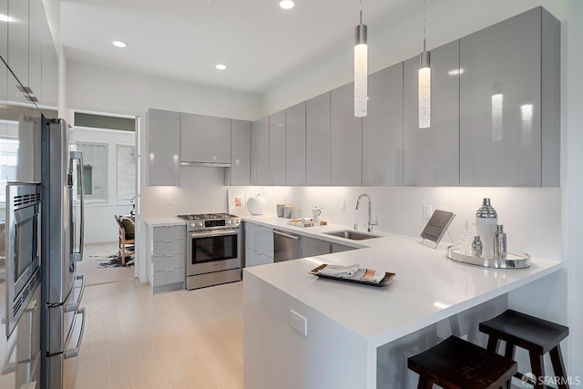 kitchen featuring gray cabinets, pendant lighting, sink, kitchen peninsula, and stainless steel appliances