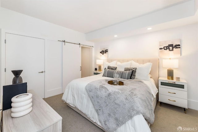 bedroom featuring light colored carpet and a barn door