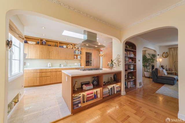 kitchen featuring island range hood, stainless steel gas stovetop, sink, light parquet floors, and built in shelves