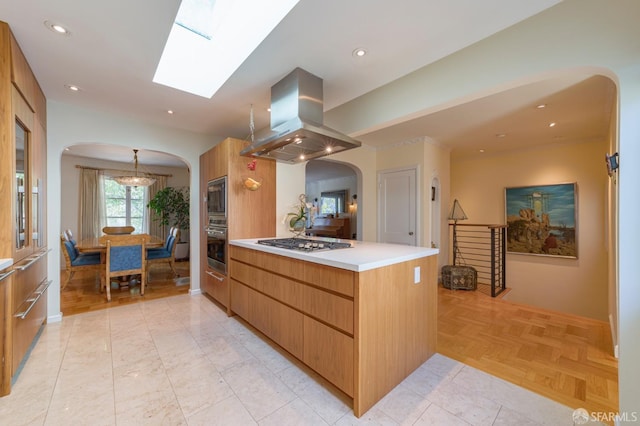 kitchen with appliances with stainless steel finishes, pendant lighting, island range hood, a skylight, and light parquet floors