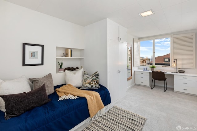 carpeted bedroom featuring built in desk