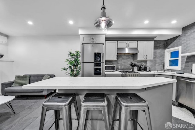 3014 Pine St Unit A, San Francisco, CA 94115 - kitchen with appliances with stainless steel finishes, under cabinet range hood, a kitchen breakfast bar, a sink, and tasteful backsplash