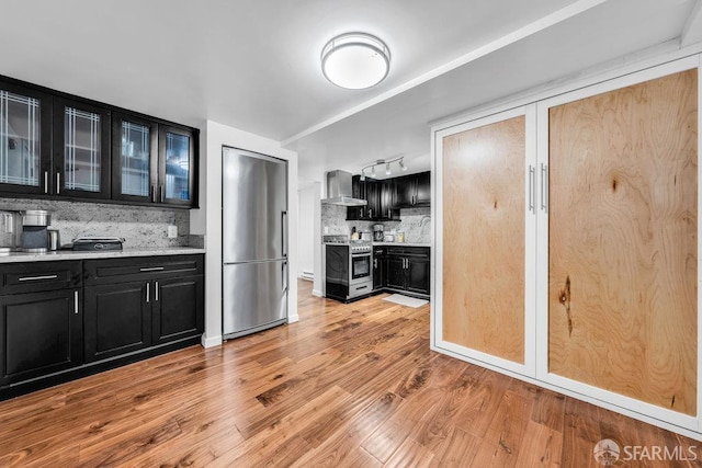 3014 Pine St Unit A, San Francisco, CA 94115 - kitchen featuring appliances with stainless steel finishes, dark cabinetry, wall chimney range hood, decorative backsplash, and light countertops