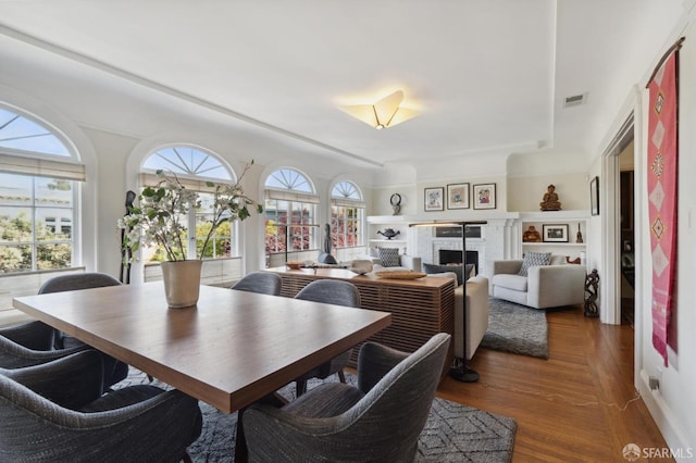 dining room with plenty of natural light, a fireplace, and wood finished floors