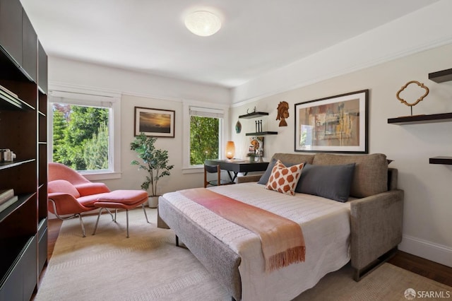 bedroom with multiple windows, baseboards, and wood finished floors