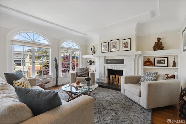 living area with dark wood finished floors, a fireplace, and built in shelves