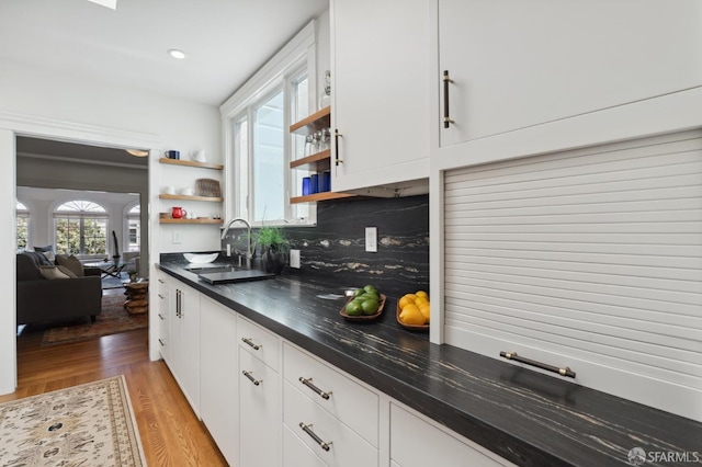 kitchen featuring open shelves, white cabinets, light wood-style floors, a sink, and tasteful backsplash