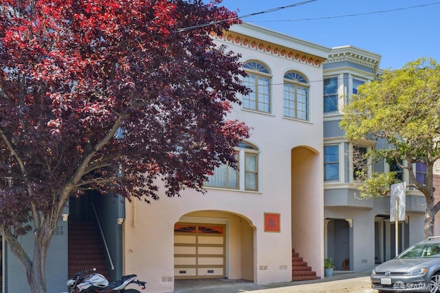 view of front of home featuring stucco siding, stairs, and an attached garage