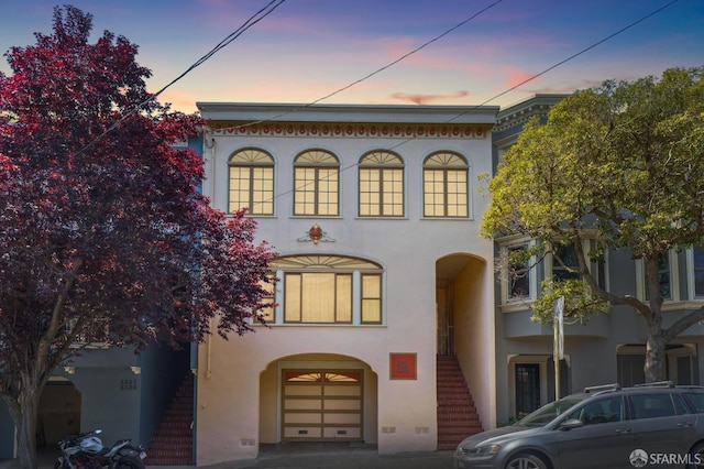 view of front of property with stairway, stucco siding, and an attached garage