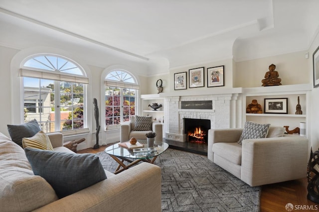 living area featuring a fireplace, wood finished floors, and built in features